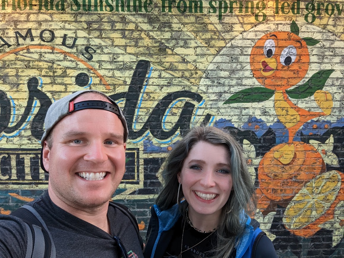 Joy and Cody in front of the Orange Bird "Florida" mural in Epcot.