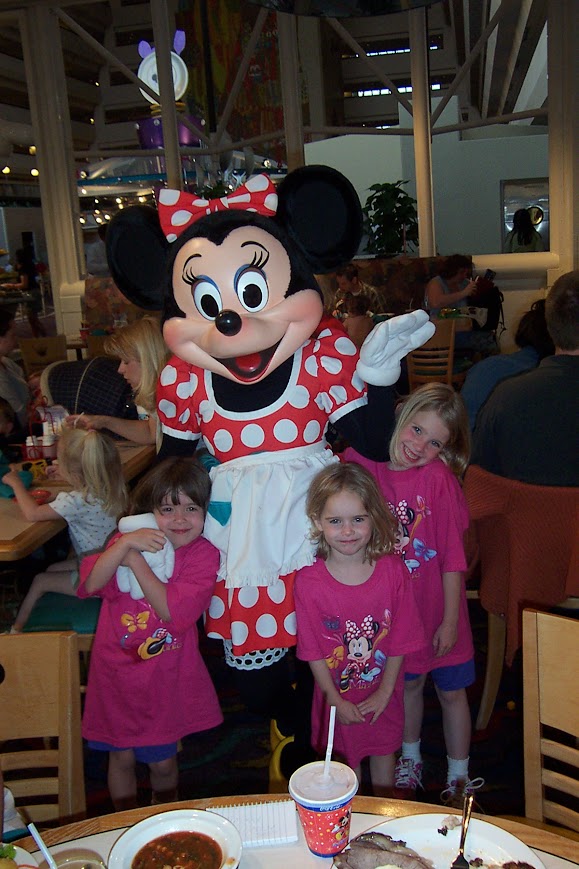 Three little girls in the early 2000s at a Disney character breakfast getting their photo taken with Minnie Mouse