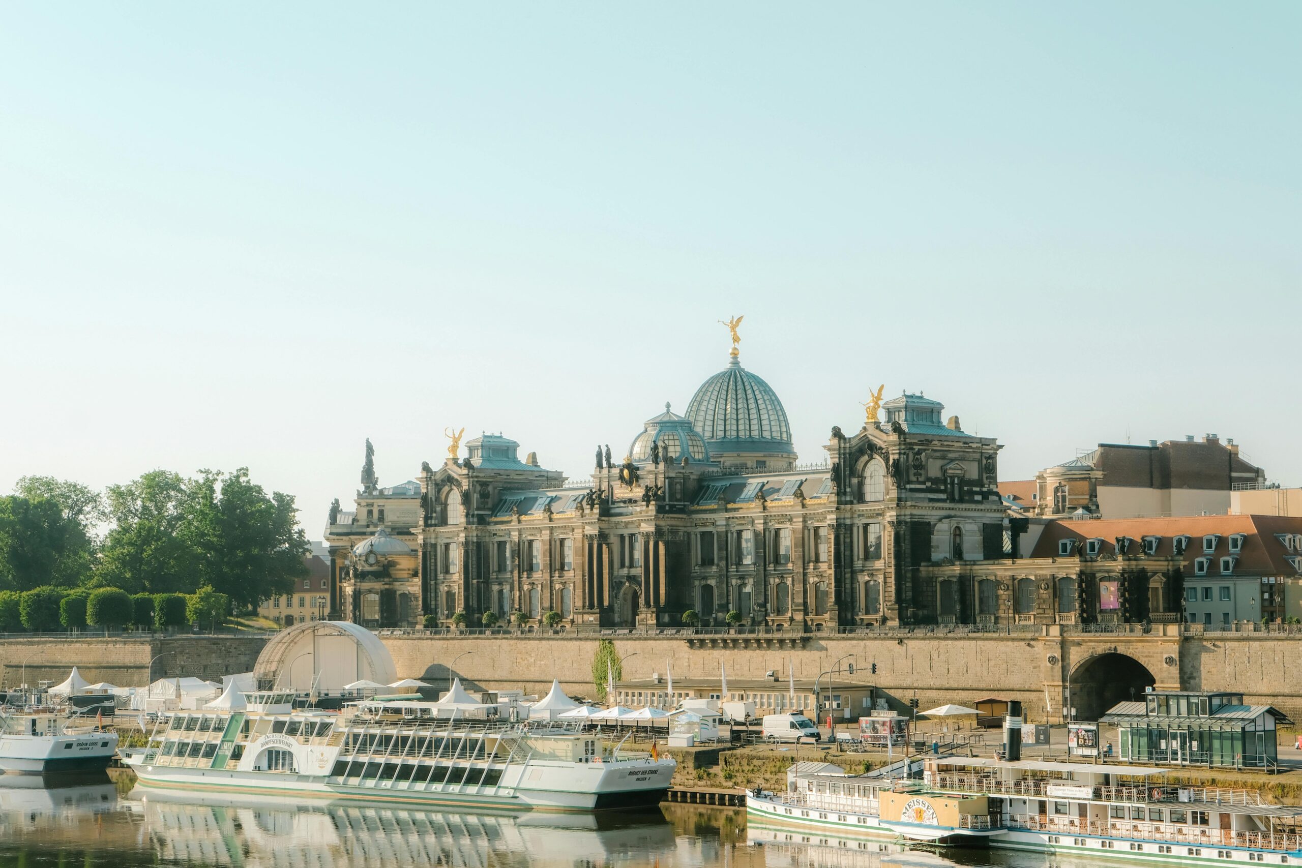 View of the Academy of Fine Arts Dresden, in Saxony, with boats on the Elbe River under a clear sky.